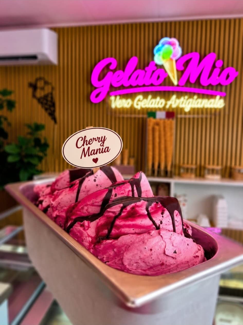 Roze Cherry Mania-gelato met chocoladesaus voor het neonlogo van Gelato Mio